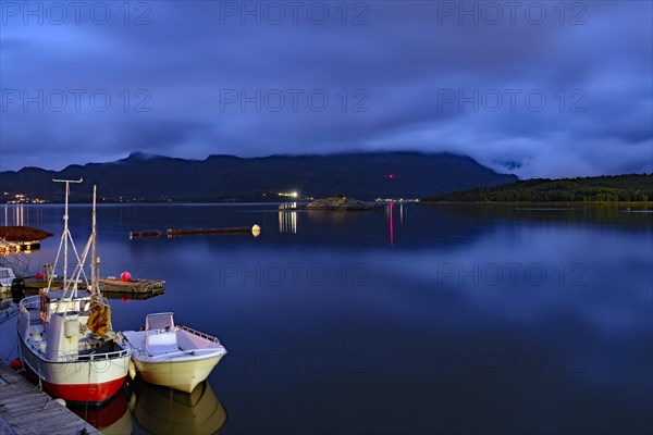 Small fishing boats reflected in the smooth water of a fjord