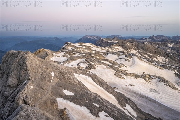 View of rocky plateau with snow and glacier at sunrise