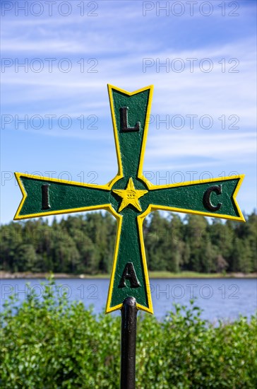 Old historical iron cross of paws with Masonic symbolism in a grove in front of Laeckoe Castle by Lake Vaenern