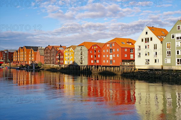 Old warehouses and storehouses reflected in the calm waters of the river Nidarelva