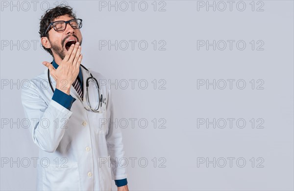 Young sleepy doctor yawning on isolated background. Tired of working doctor concept