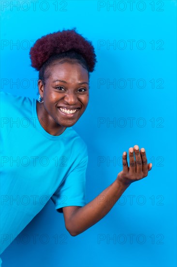 Young african american woman isolated on a blue background inviting to come with her hand