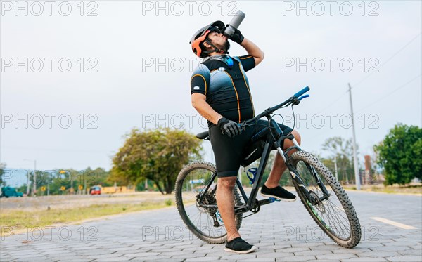 Chubby cyclist on his bike drinking water