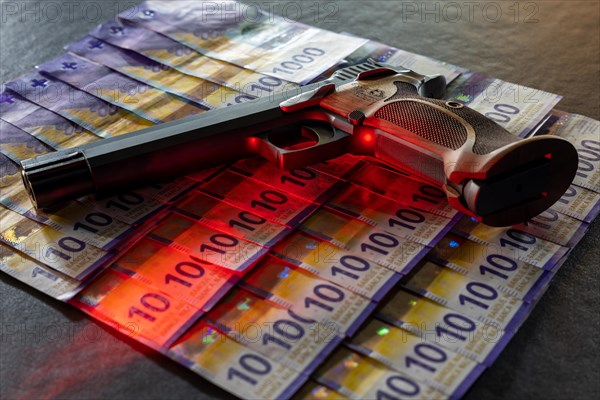 Elegant Semiautomatic 9mm Handgun with Swiss Helvetia Symbol Leaning on Swiss Franc 1000 Banknote in Switzerland