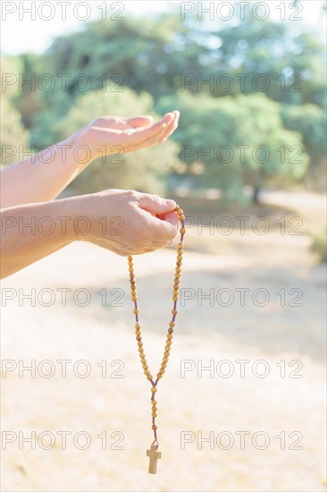 Woman's hands holding a Christian rosary with a cross