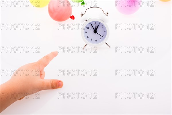 Hand pointing an alarm clock with balloons on the white background