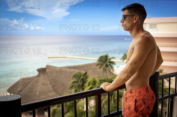 Young handsome boy in swimsuit in caribbean on balcony of all inclusive hotel