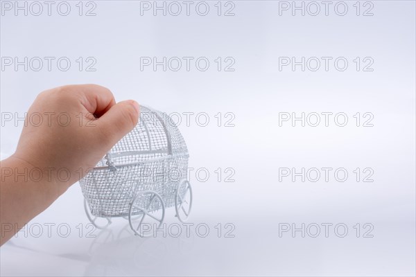 Toy baby carriage in hand made of metal on white background