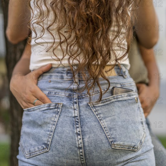 Close up of a woman hugging her girlfriend. She puts on hand in her girlfriend's back pocket