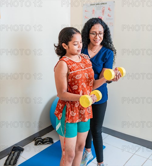 Physiotherapist helping patient with dumbbells