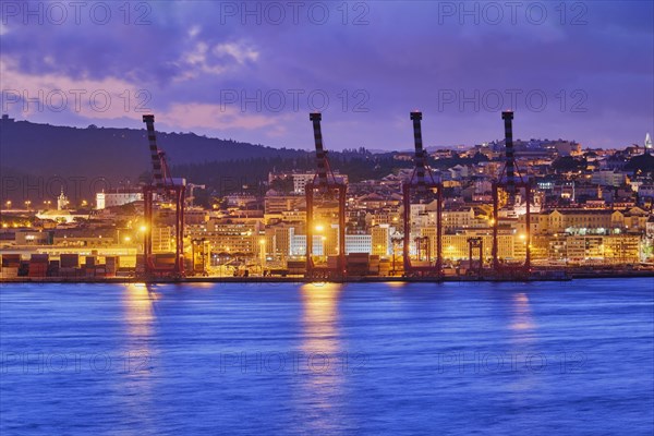 View of Lisbon port with port cranes in the evening twilight over Tagus river. Lisbon