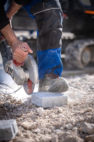 Man with flex saws stones on building site