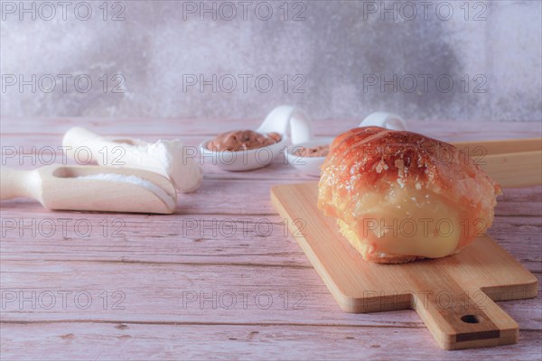 Puff pastry horn filled with pastry cream with some spoons with cocoa