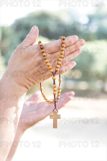 Woman's hands holding a Christian rosary with a cross