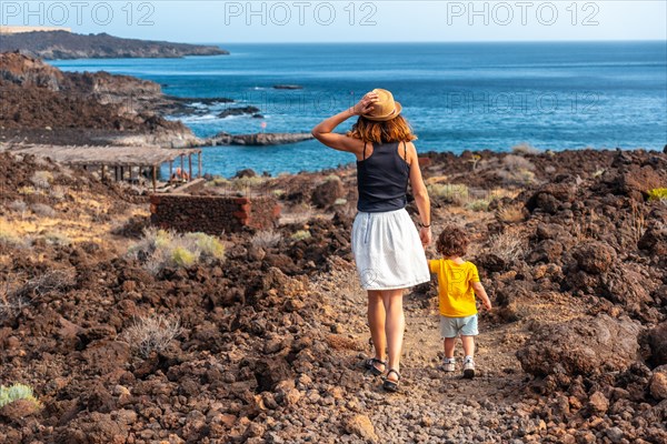 Mother and son on vacation walking on a path along the beach of Tacoron on El Hierro