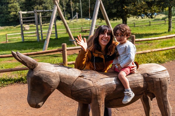 A boy and a mother playing on the wooden horse in the leisure area at Laguna Grande in the Garajonay natural park on La Gomera