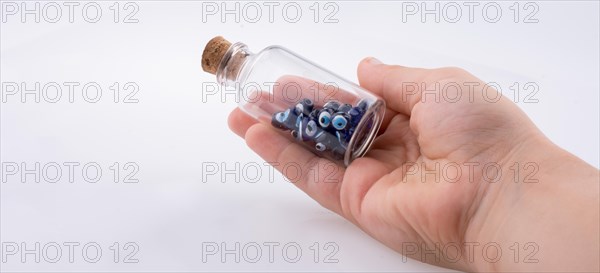 Little glass bottle with blue evil eye bead in hand