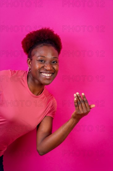 Young african american woman isolated on a pink background inviting to come with her hand