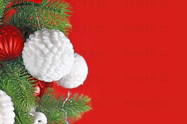 Fluffy white Christmas bauble on decorated tree with red background