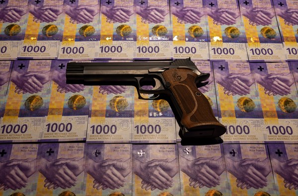 Elegant Semiautomatic 9mm Handgun with Swiss Helvetia Symbol Leaning on Swiss Franc 1000 Banknote in Switzerland