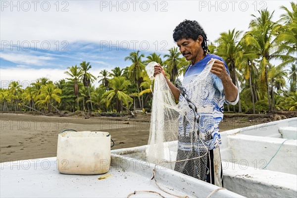 A rustic local fisherman preparing his net on the shore to start the day's work