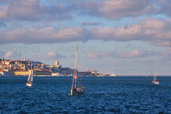View of Lisbon over Tagus river from Almada with yachts tourist boats on sunset with dramatic sky. Lisbon