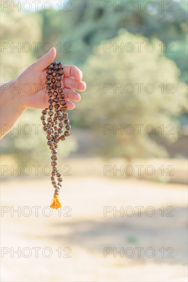 Woman's hands holding a hindu japa mala illuminated by sun in meditation in the countryside at sunset