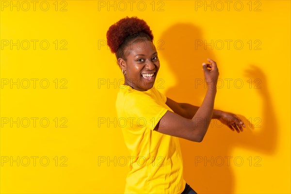 Young african american woman isolated on a yellow background smiling and dancing