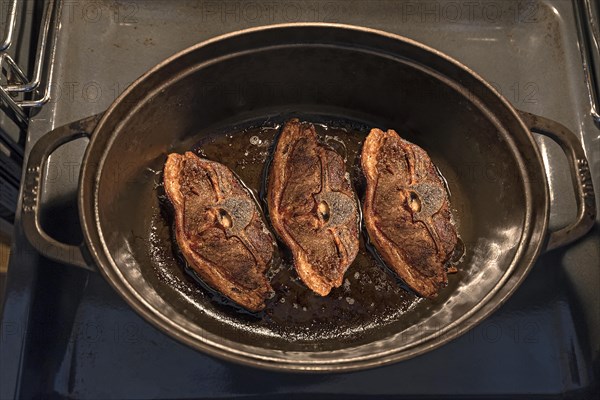 Three freshly roasted lamb cutlets in a casserole on a tray in the oven