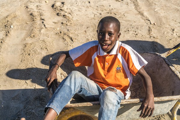 Laughing boy sitting in a wheelbarrow