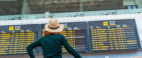 Unrecognizable tourist woman at the airport looking at information on screens in the connection terminal