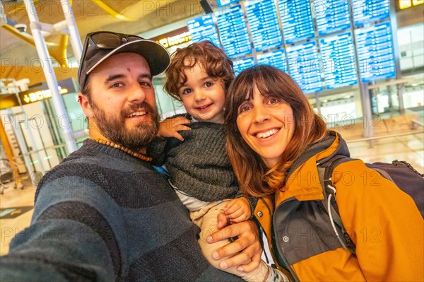 Tourist family at the airport looking at information on screens in the connection terminal