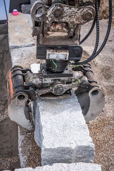 Excavator grab with stone on construction site