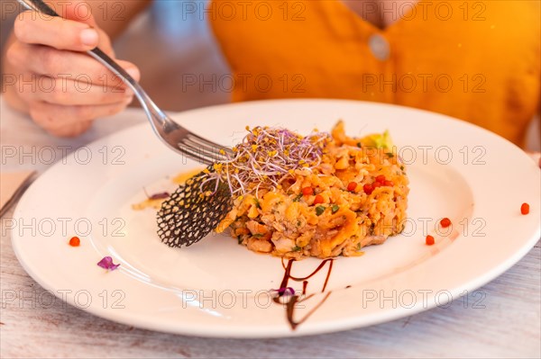 Detail with a female hand dining in a restaurant on the beach on vacation at sunset