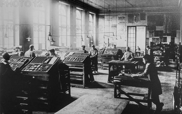 Early 20th century typesetters arranging types called typesetting for letterpress printing in print shop