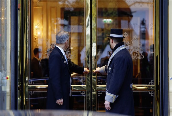A uniformed car attendant and a concierge of the Hotel Imperial open the hotel door