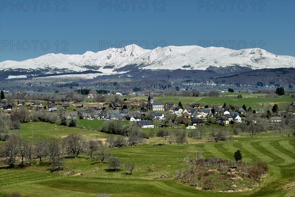 Regional natural park of the Volcanoes of Auvergne. View on the village of Saint Genes Champespe and the Monts Dore in winter. Puy de Dome department. Auvergne-Rhone-Alpes. France