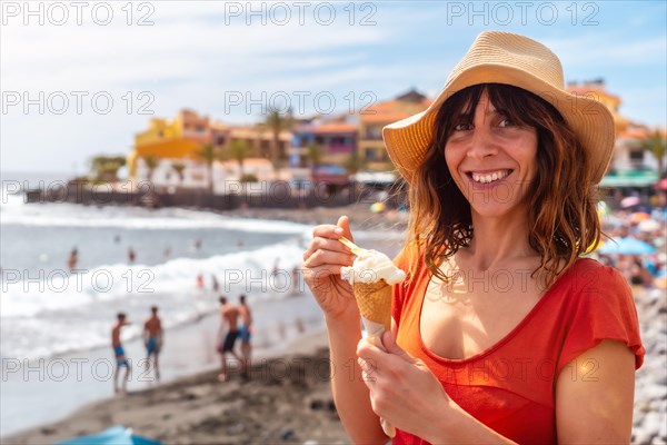 Tourist woman with a hat eating an ice cream on the beach in summer on the beach of Valle Gran Rey on La Gomera