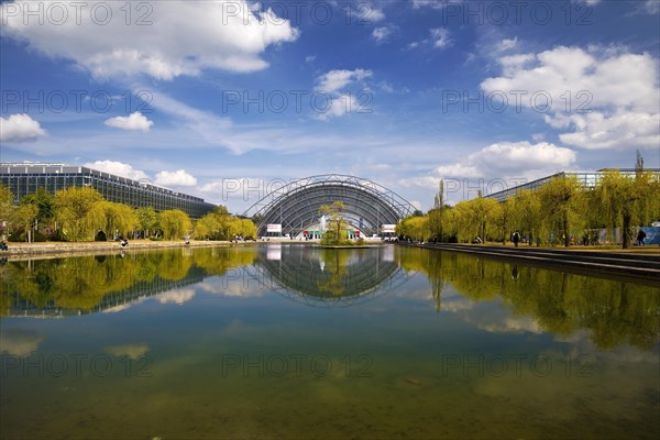 Glass hall with reflection in the water basin in front of the main entrance to the Leipzig Trade Fair