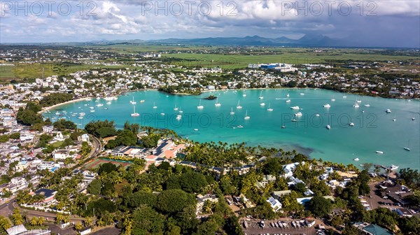 Aerial view from bird's eye view of large sea bay Grand Baie with pleasure boats motor yachts sailboats anchored in sheltered bay