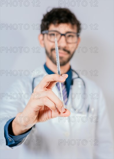 Close up of doctor holding a syringe isolated. Smiling doctor holding a syringe on isolated background