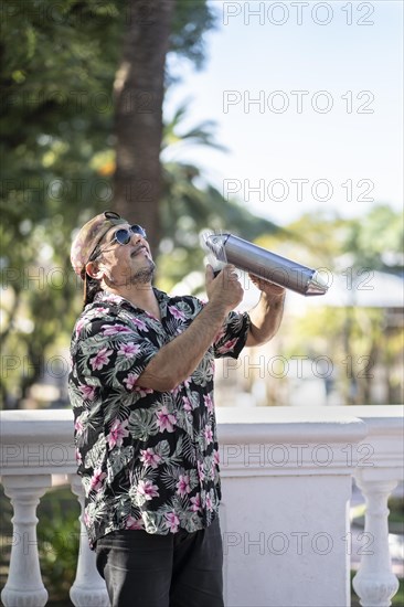 Hispanic artist playing gueiro in the street