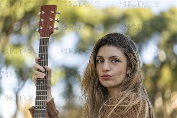 Young blonde woman with her guitar in the park. Concept of creative hobbiess and professionals. Positive attitude. Empowerment