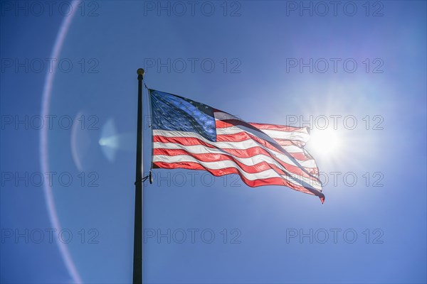 US flag waving in the wind. Vibrant colors over blue sky
