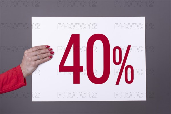 Female hand holding a 40% poster. Studio shot. Commercial concept