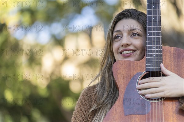 Young blonde woman with her guitar in the park. Concept of creative hobbiess and professionals. Positive attitude. Empowerment