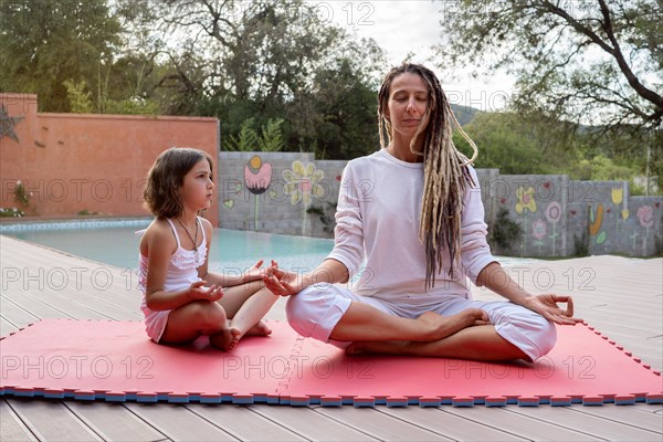 Blonde rasta mother with her little daughter sitting in lotus position. Meditation and relaxation