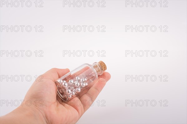 Little perfume glass bottle in hand on a white background