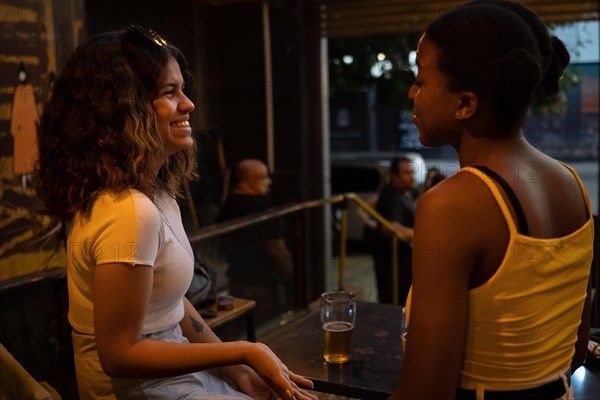 Women sitting at table in pub talking and laugh. Multiethnic concept