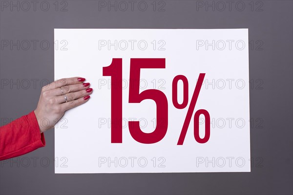 Female hand holding a 15% poster. Studio shot. Commercial concept